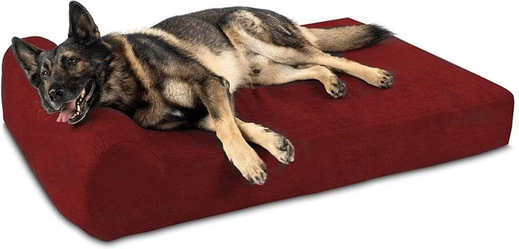A German Shepherd dog lying on a large, plush, deep red rectangular dog bed against a plain white background.